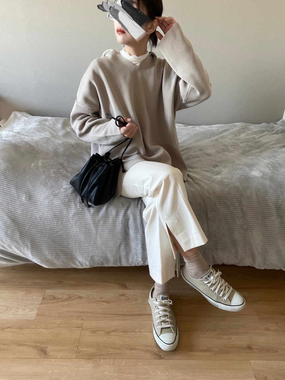 ベージュ系のスニーカー、ブラック系のショルダーバッグ、ベージュ系のニット/セーターを着用したレディースの冬コーディネートの1枚目の写真