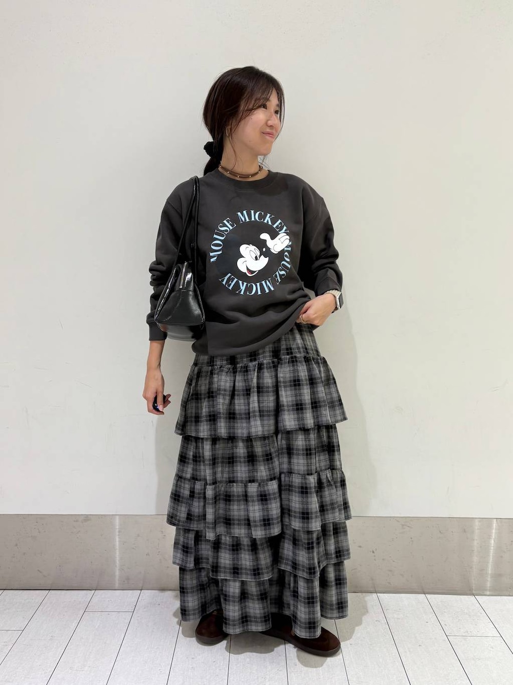 ブラウン系のスニーカー、グレー系のスカート、ブラック系のボストンバッグを着用したレディースの秋コーディネートの1枚目の写真