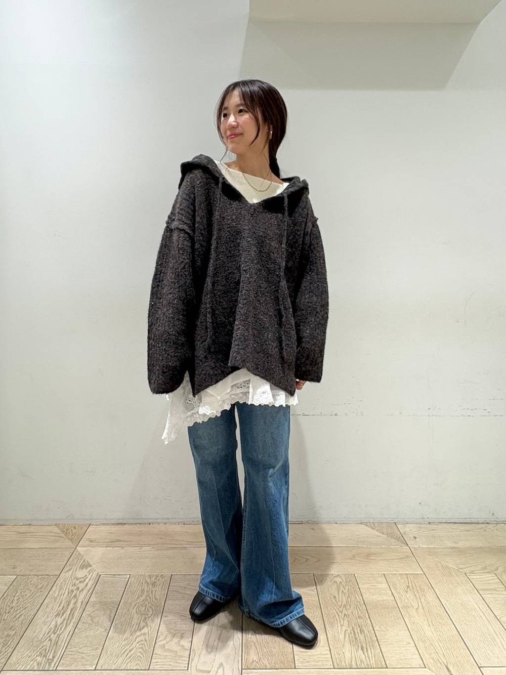 グレー系のニット/セーター、ホワイト系のスカート、ブルー系のデニムパンツを着用したレディースの秋コーディネートの1枚目の写真