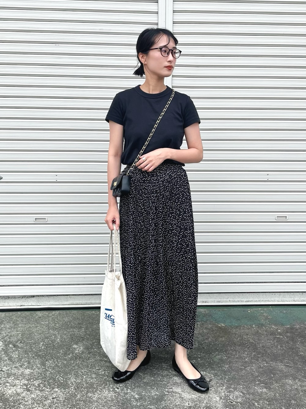ブラック系のスカート、ブラック系のTシャツ/カットソー、ブラック系のショルダーバッグを着用したレディースの春コーディネートの1枚目の写真