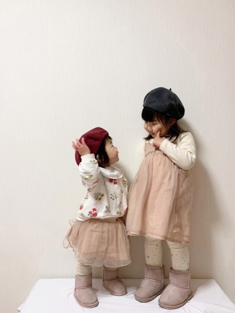 ベージュ系のワンピース、ホワイト系のスウェット、ピンク系のブーツを着用したキッズの冬コーディネートの1枚目の写真