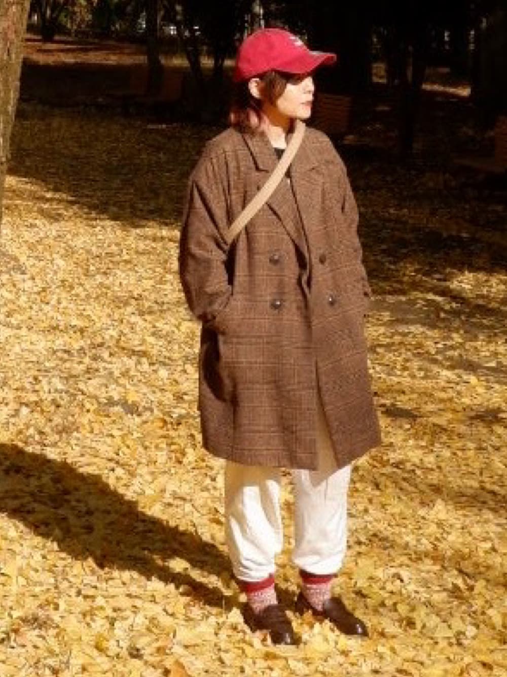 ブラウン系のレインシューズ、ブラウン系のチェスターコート、ベージュ系のショルダーバッグを着用したメンズの秋コーディネートの1枚目の写真