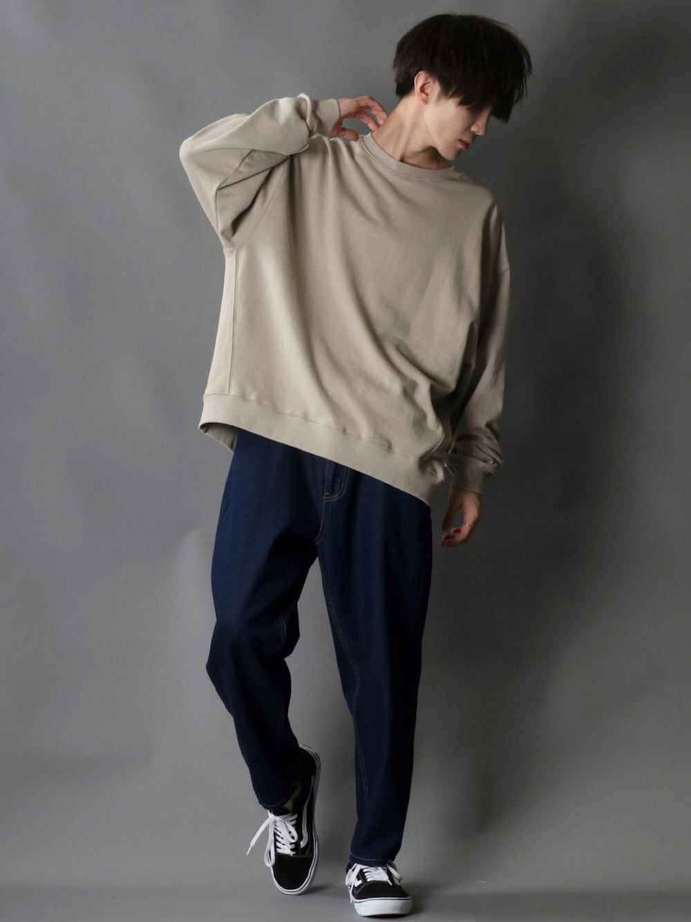 ベージュ系のスウェット、ブルー系のデニムパンツ、ブラック系のスニーカーを着用したメンズの秋コーディネートの1枚目の写真