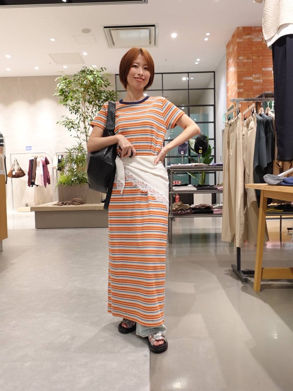 ブルー系のデニムパンツ、シルバー系のサンダル、オレンジ系のワンピースを着用したレディースの春コーディネートの1枚目の写真