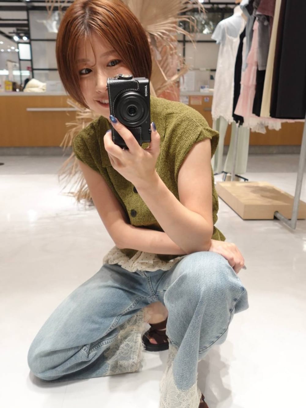 グリーン系のベスト、ブルー系のデニムパンツ、ブラウン系のサンダルを着用したレディースの夏コーディネートの1枚目の写真