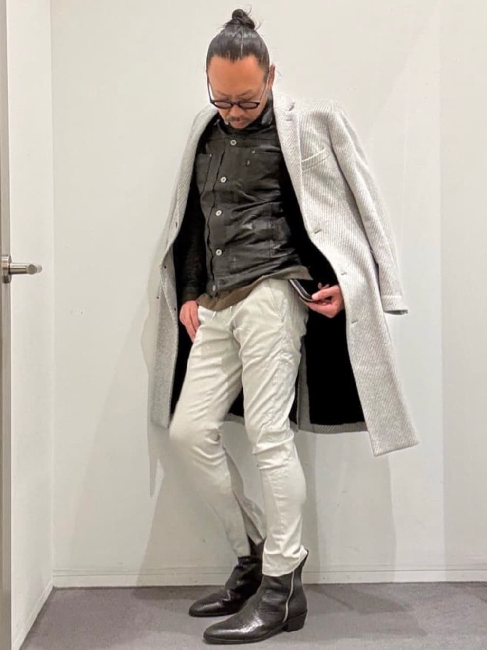 グレー系のチェスターコート、ブラック系のライダースジャケット、グリーン系のTシャツ/カットソーを着用したメンズの秋コーディネートの1枚目の写真
