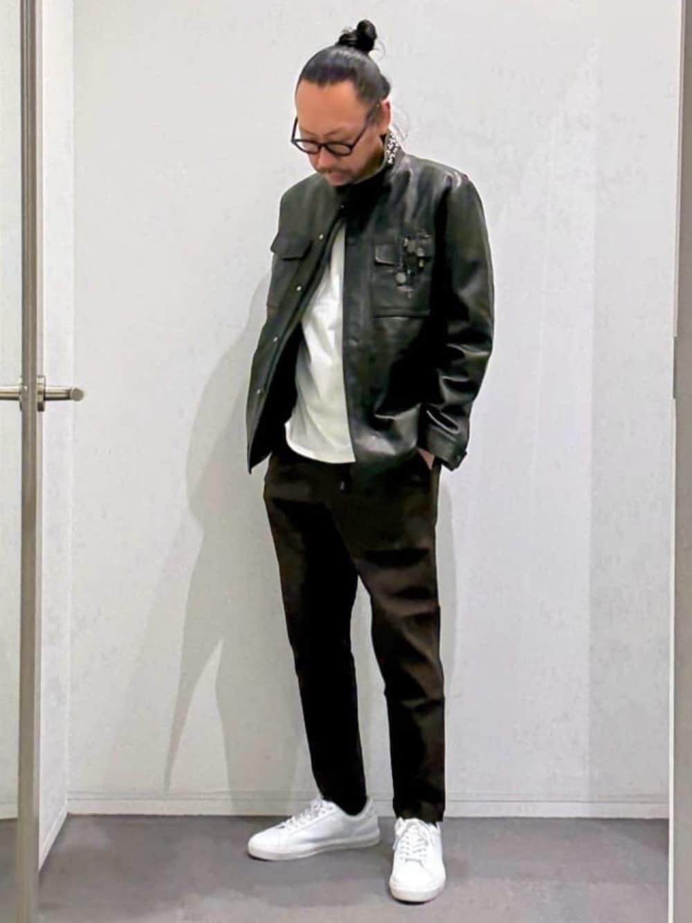 ブラック系のライダースジャケット、ホワイト系のスニーカーを着用したメンズの春コーディネートの1枚目の写真