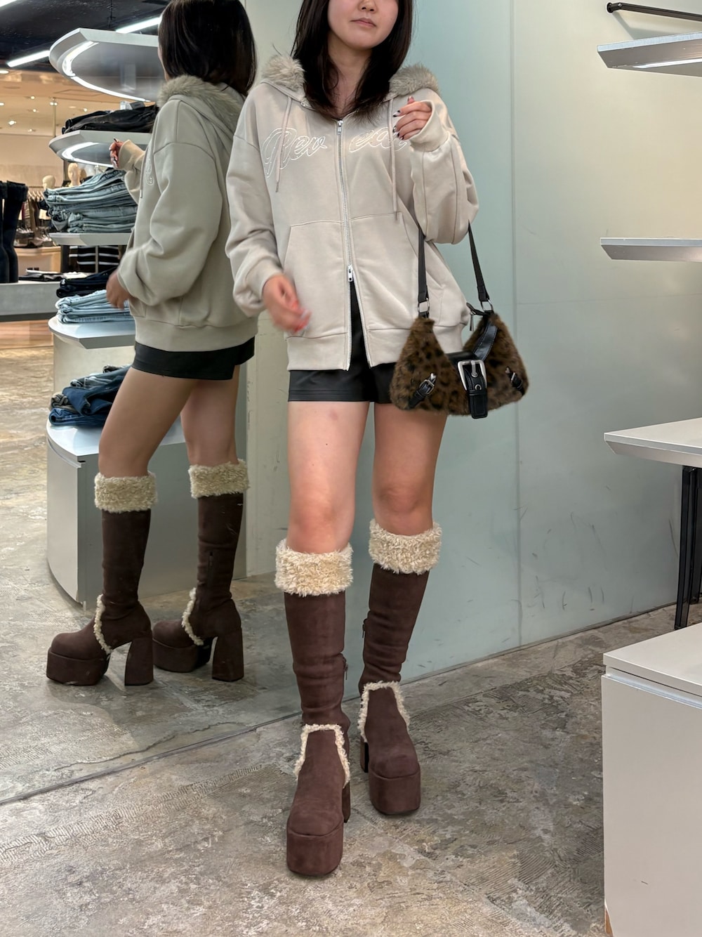 ブラウン系のブーツ、ベージュ系のパーカー、ブラック系のその他パンツを着用したレディースの秋コーディネートの1枚目の写真