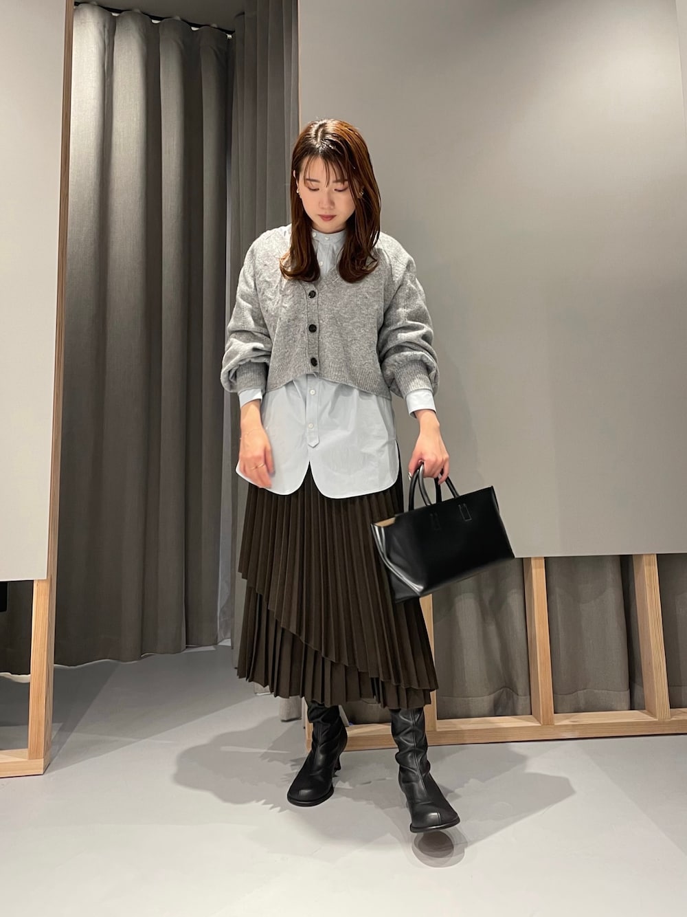 グレー系のカーディガン/ボレロ、ブルー系のシャツ/ブラウス、ブラウン系のスカートを着用したレディースの秋コーディネートの1枚目の写真