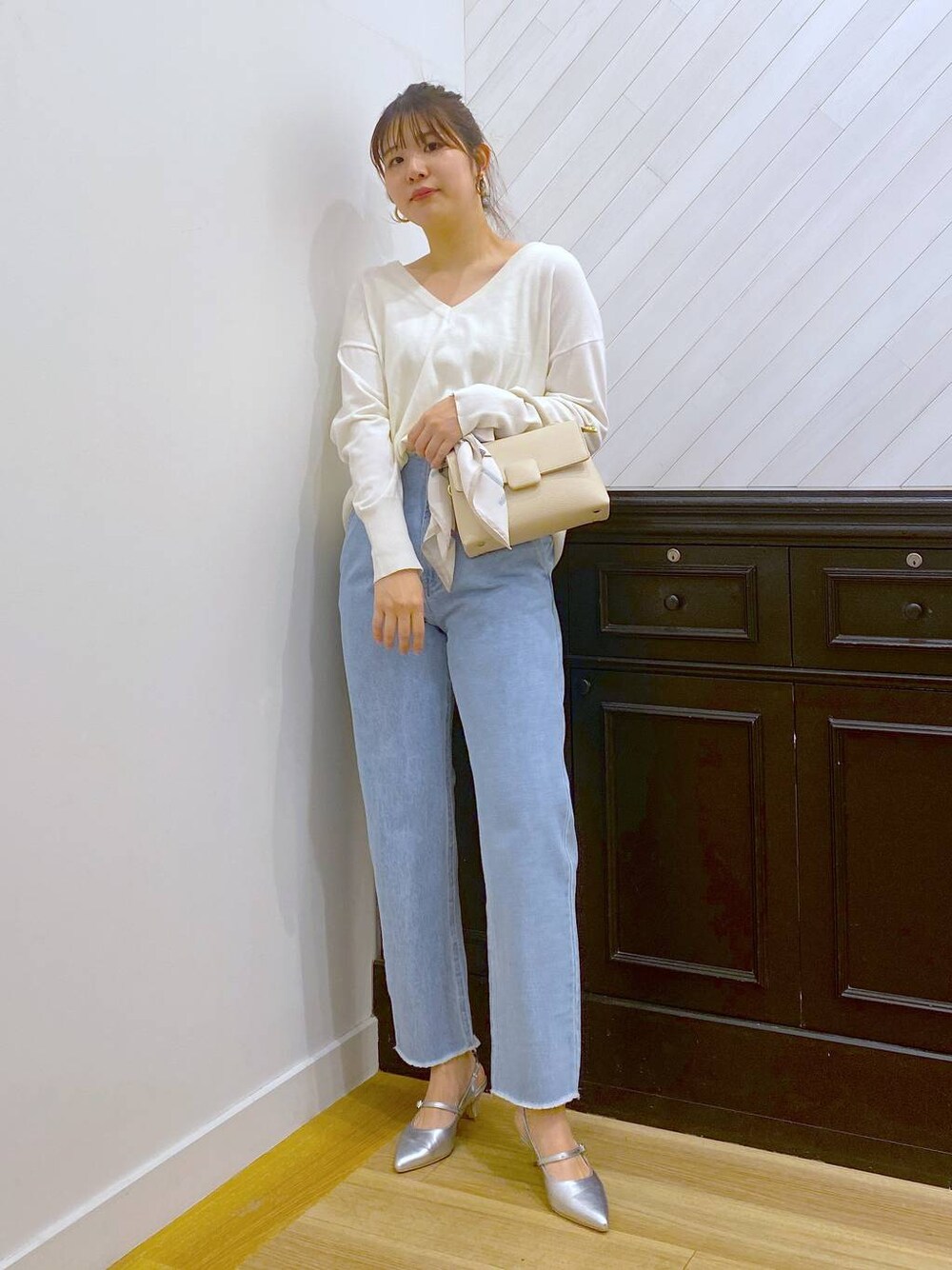 ホワイト系のハンドバッグ、ブルー系のデニムパンツ、シルバー系のサンダルを着用したレディースの春コーディネートの1枚目の写真