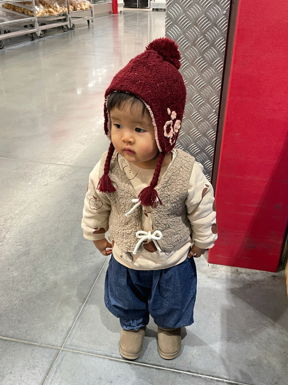 ホワイト系のスウェット、ベージュ系のベスト、ブルー系のデニムパンツを着用したキッズの冬コーディネートの1枚目の写真