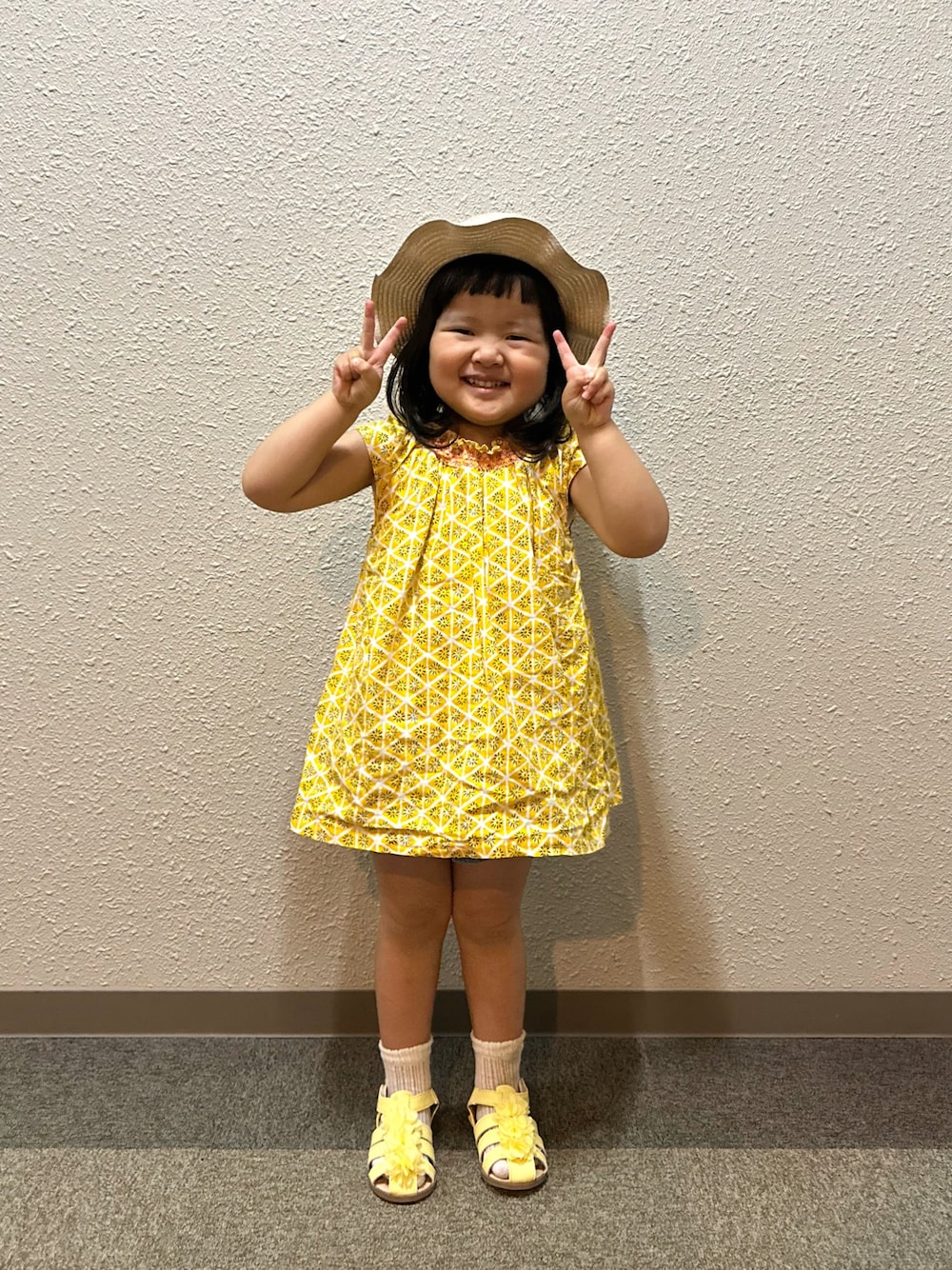 イエロー系のチュニック、ブルー系のデニムパンツ、イエロー系のサンダルを着用したキッズの夏コーディネートの1枚目の写真