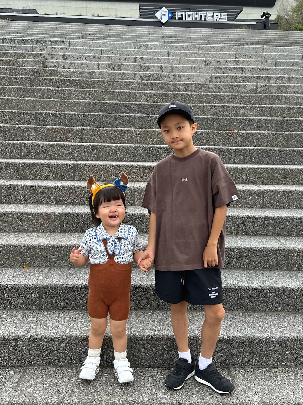 ブラウン系のTシャツ/カットソー、ブラック系のパンツ、ブラック系のスニーカーを着用したキッズの秋コーディネートの1枚目の写真