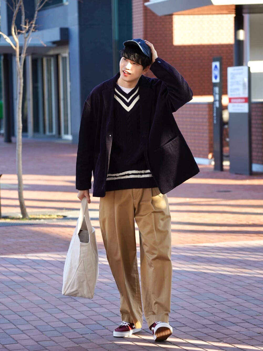 ブルー系のニット/セーター、ブラウン系のその他パンツ、ベージュ系のトートバッグを着用したメンズの冬コーディネートの1枚目の写真