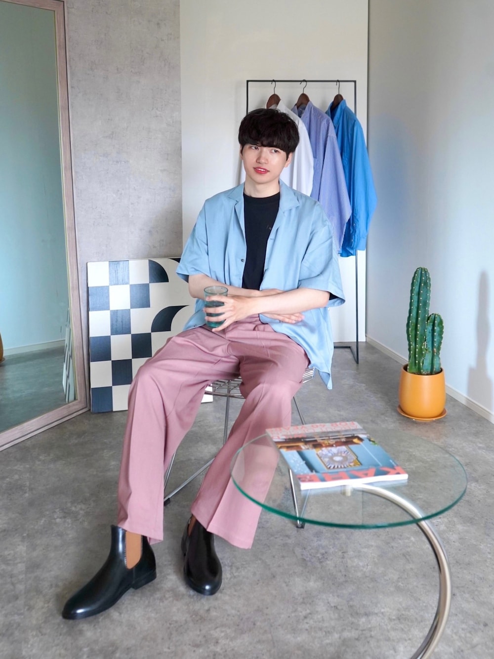 ピンク系のスラックス、ブラック系のTシャツ/カットソー、ブラウン系のレインシューズを着用したメンズの夏コーディネートの1枚目の写真