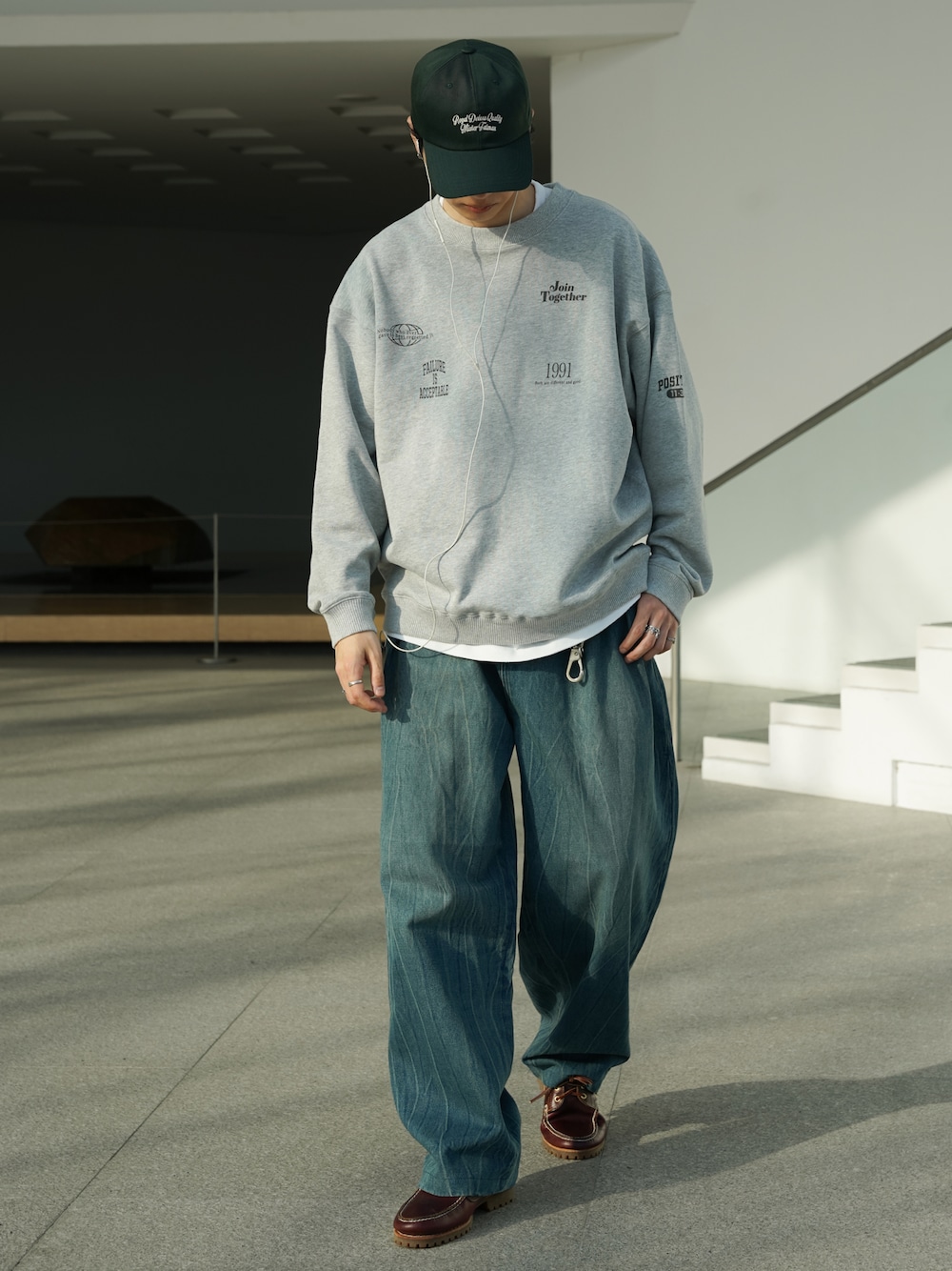 レッド系のブーツ、ブルー系のデニムパンツ、グレー系のスウェットを着用したメンズの春コーディネートの1枚目の写真