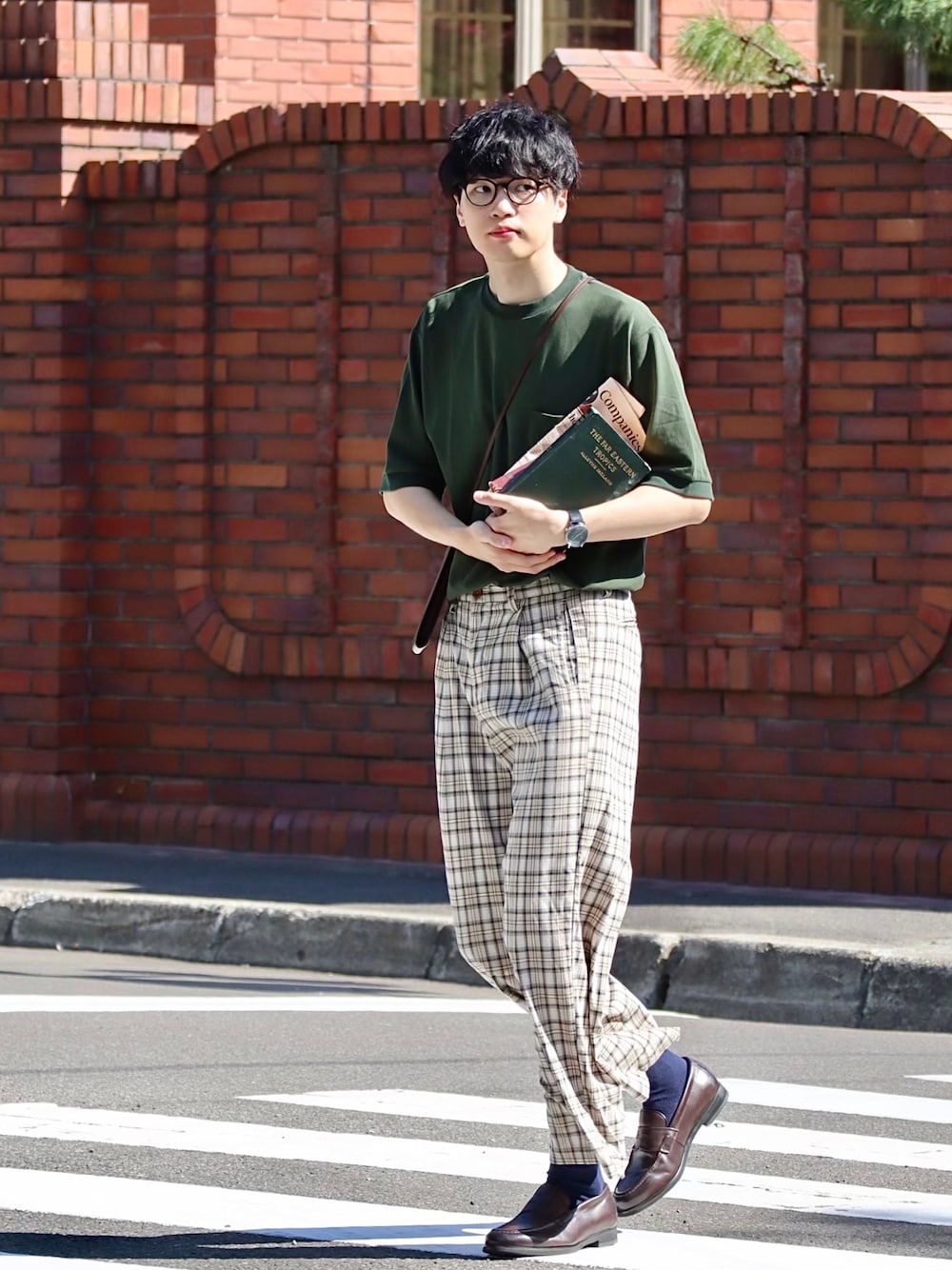 グリーン系のTシャツ/カットソー、ブラウン系のショルダーバッグ、ブラック系のメガネを着用したメンズの秋コーディネートの1枚目の写真