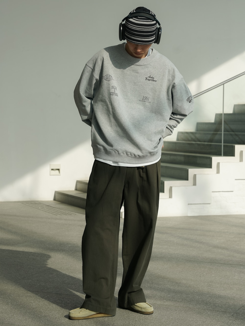 グレー系のスウェット、グリーン系のデニムパンツ、ベージュ系のブーツを着用したメンズの春コーディネートの1枚目の写真