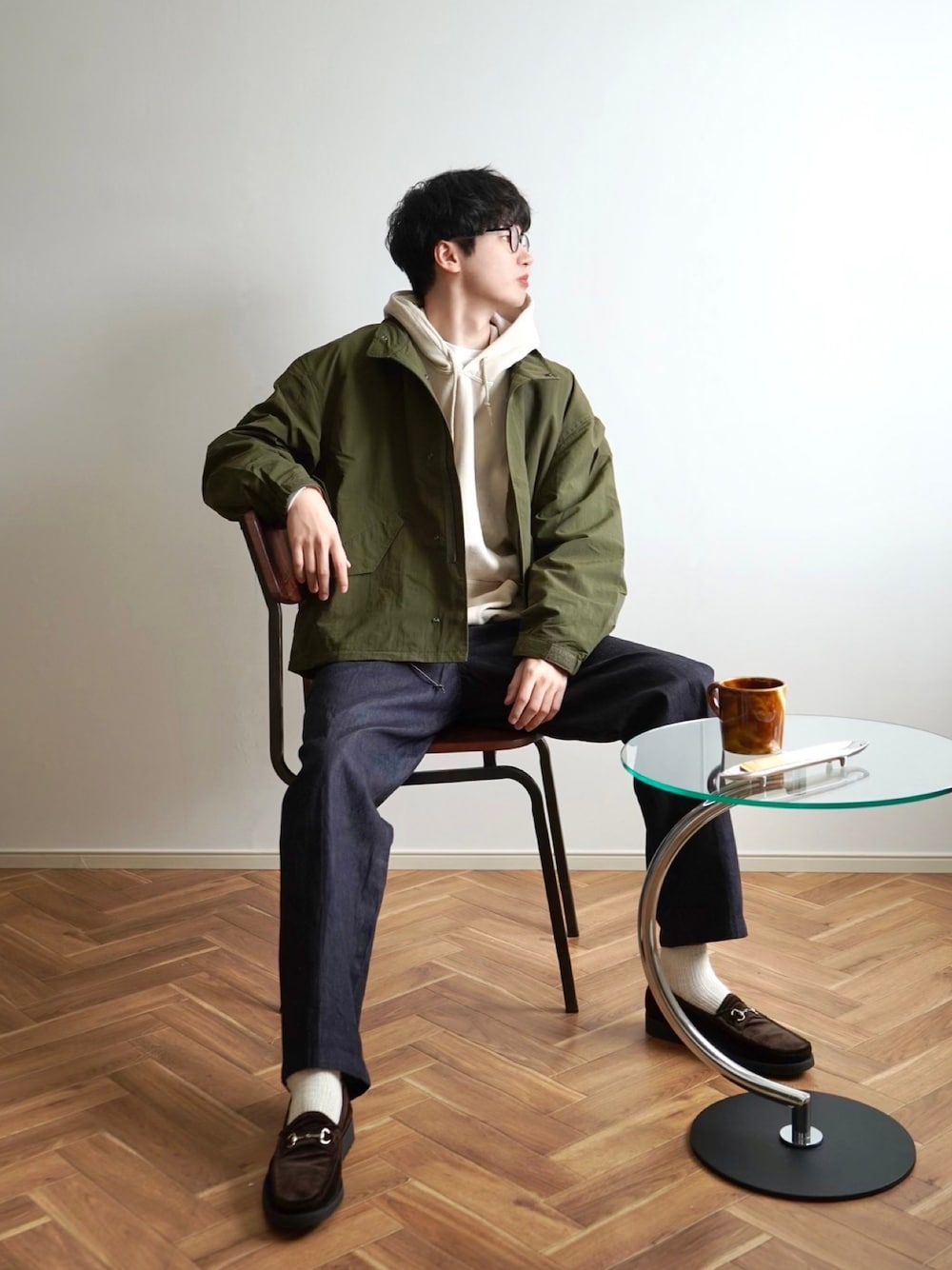 グリーン系のモッズコート、ベージュ系のパーカー、ブルー系のデニムパンツを着用したメンズの春コーディネートの1枚目の写真