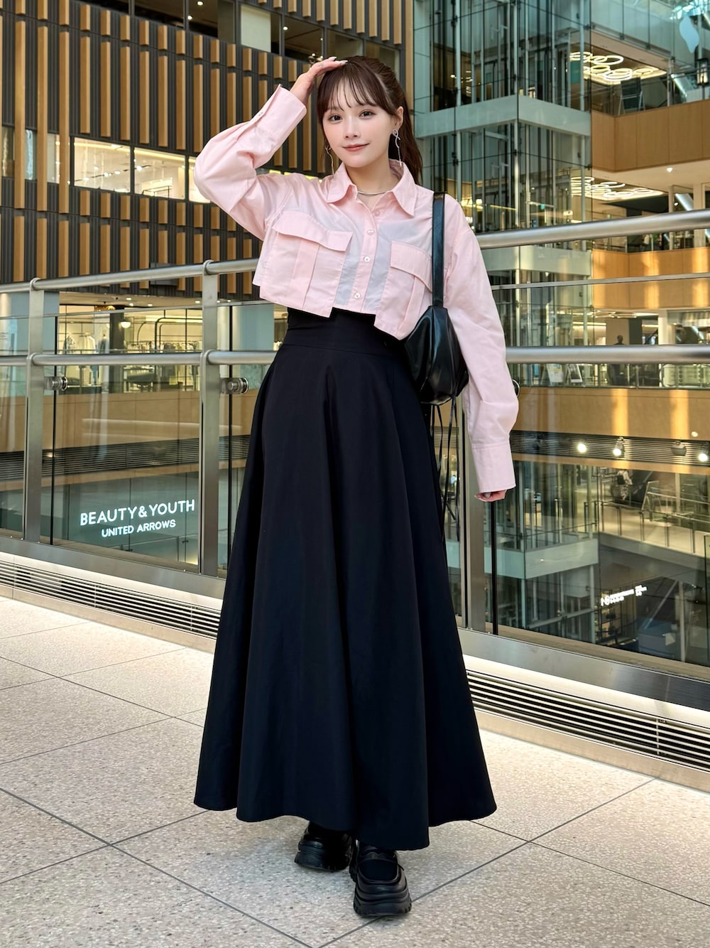 ブラック系のスカート、ピンク系のトップス、ブラック系のローファーを着用したレディースの春コーディネートの1枚目の写真