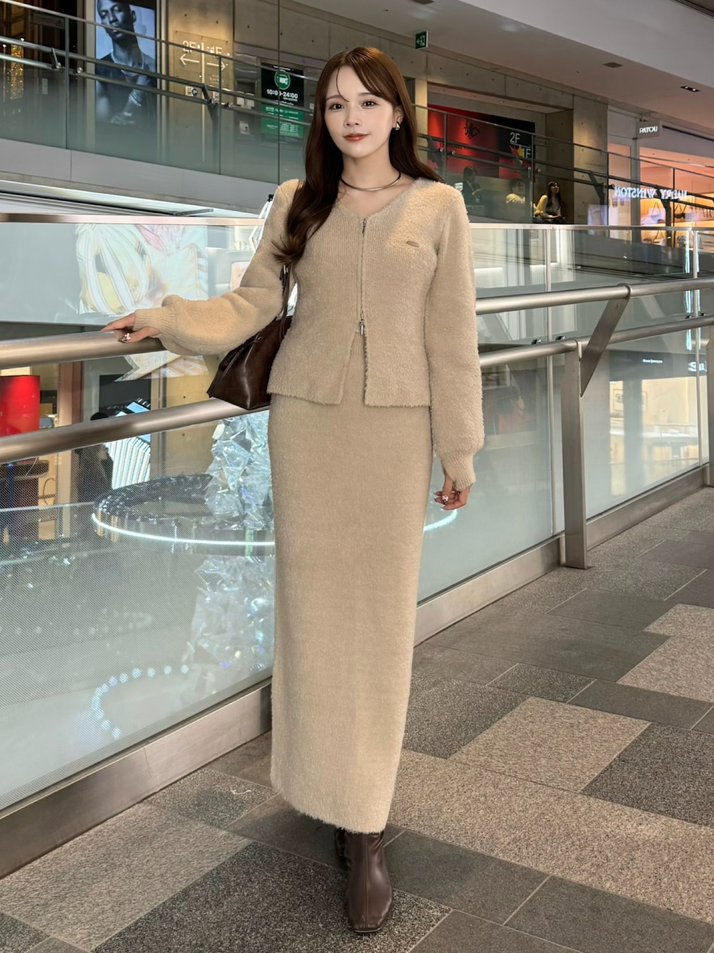 ベージュ系のカーディガン/ボレロ、ベージュ系のスカート、ブラウン系のショルダーバッグを着用したレディースの冬コーディネートの1枚目の写真