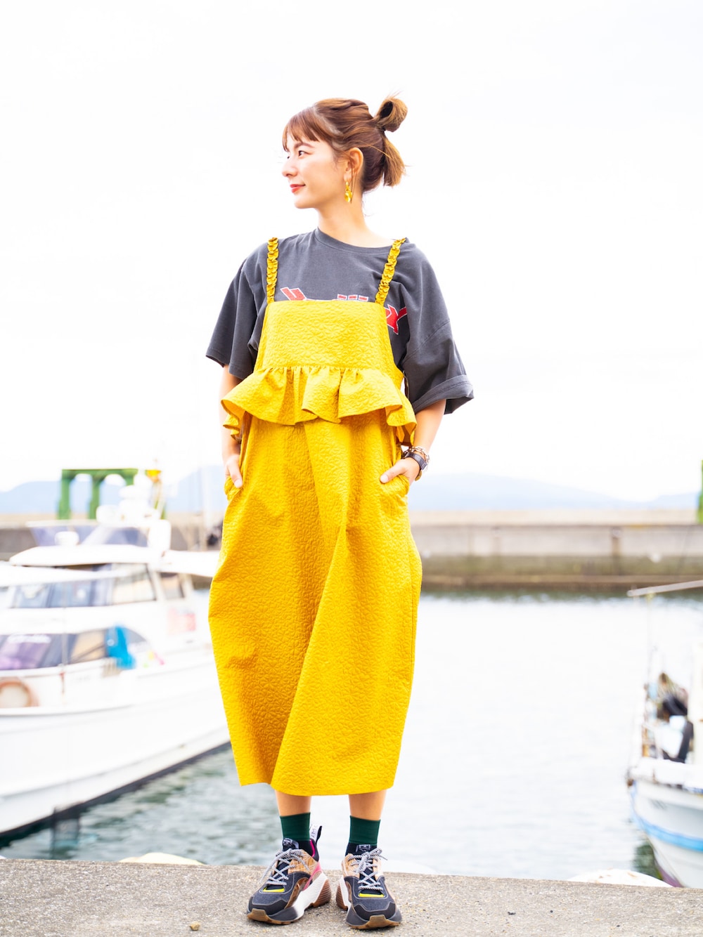 イエロー系のワンピース、その他のスニーカー、ブラック系のTシャツ/カットソーを着用したレディースの秋コーディネートの1枚目の写真