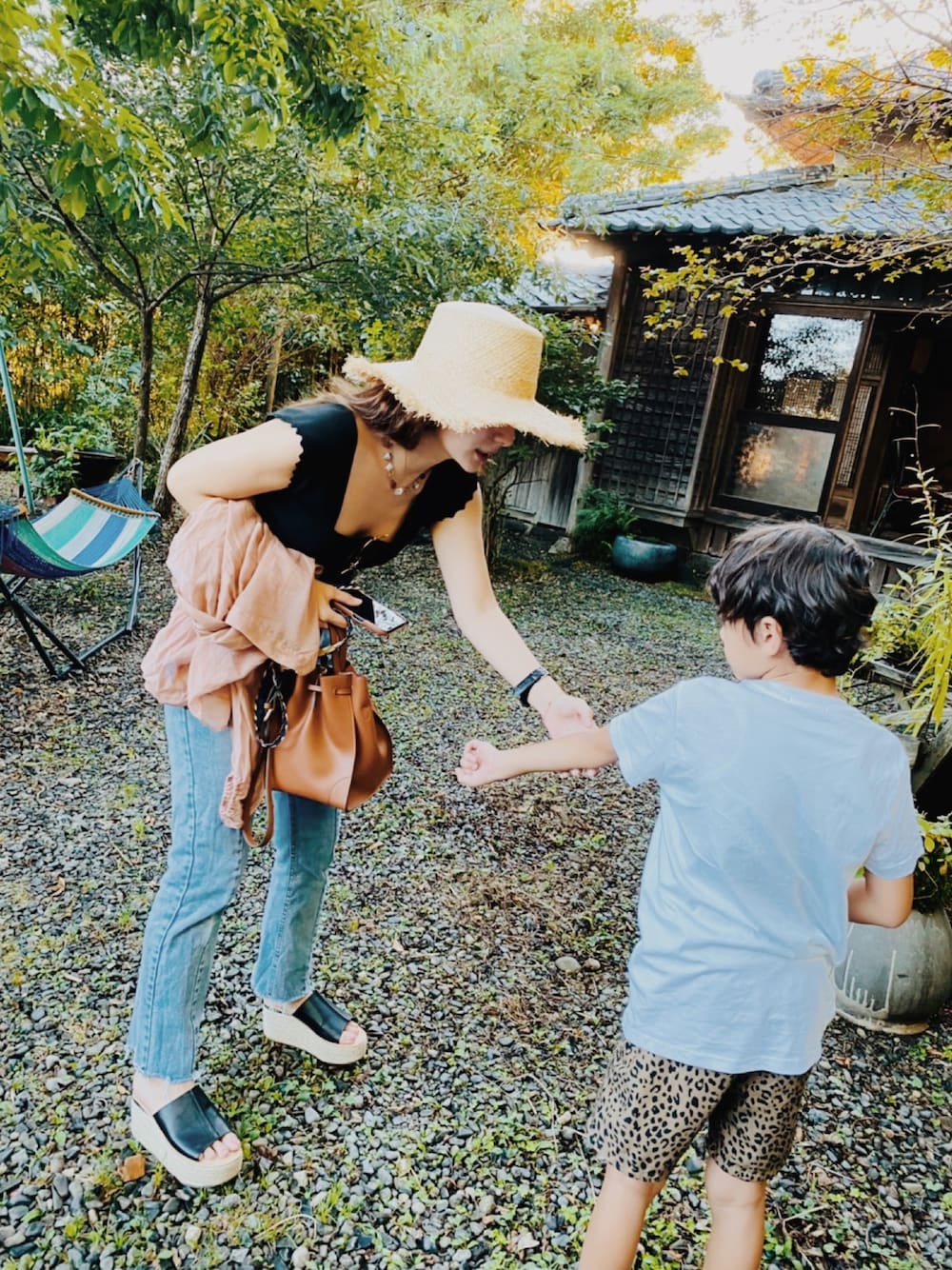 ブラック系のサンダル、ブルー系のデニムパンツ、ブラウン系のバッグを着用したレディースの夏コーディネートの1枚目の写真