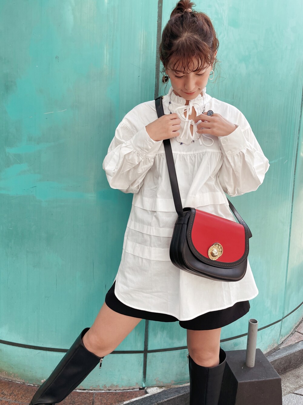 レッド系のトートバッグ、ホワイト系のシャツ/ブラウス、ブラック系のブーツを着用したレディースの秋コーディネートの1枚目の写真