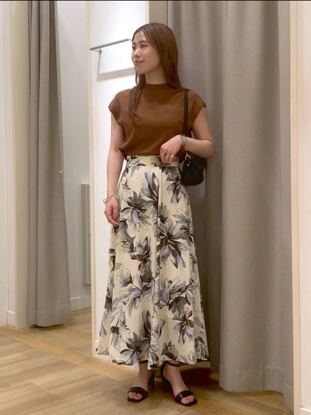 ホワイト系のスカート、ブラウン系のニット/セーター、ブラック系のショルダーバッグを着用したレディースの夏コーディネートの1枚目の写真