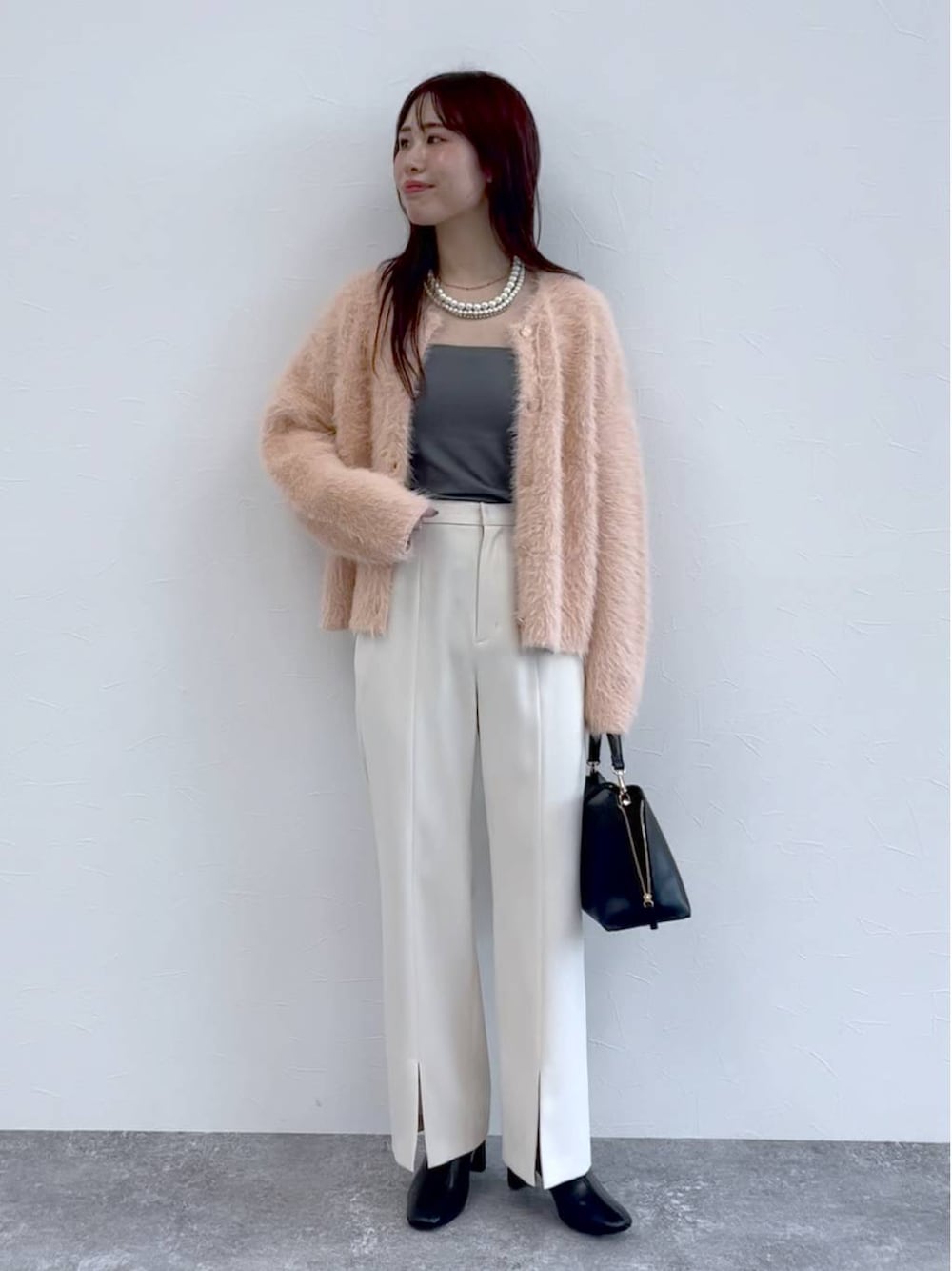 ブラック系のブーツ、ピンク系のニット/セーター、ホワイト系のスラックスを着用したレディースの秋コーディネートの1枚目の写真