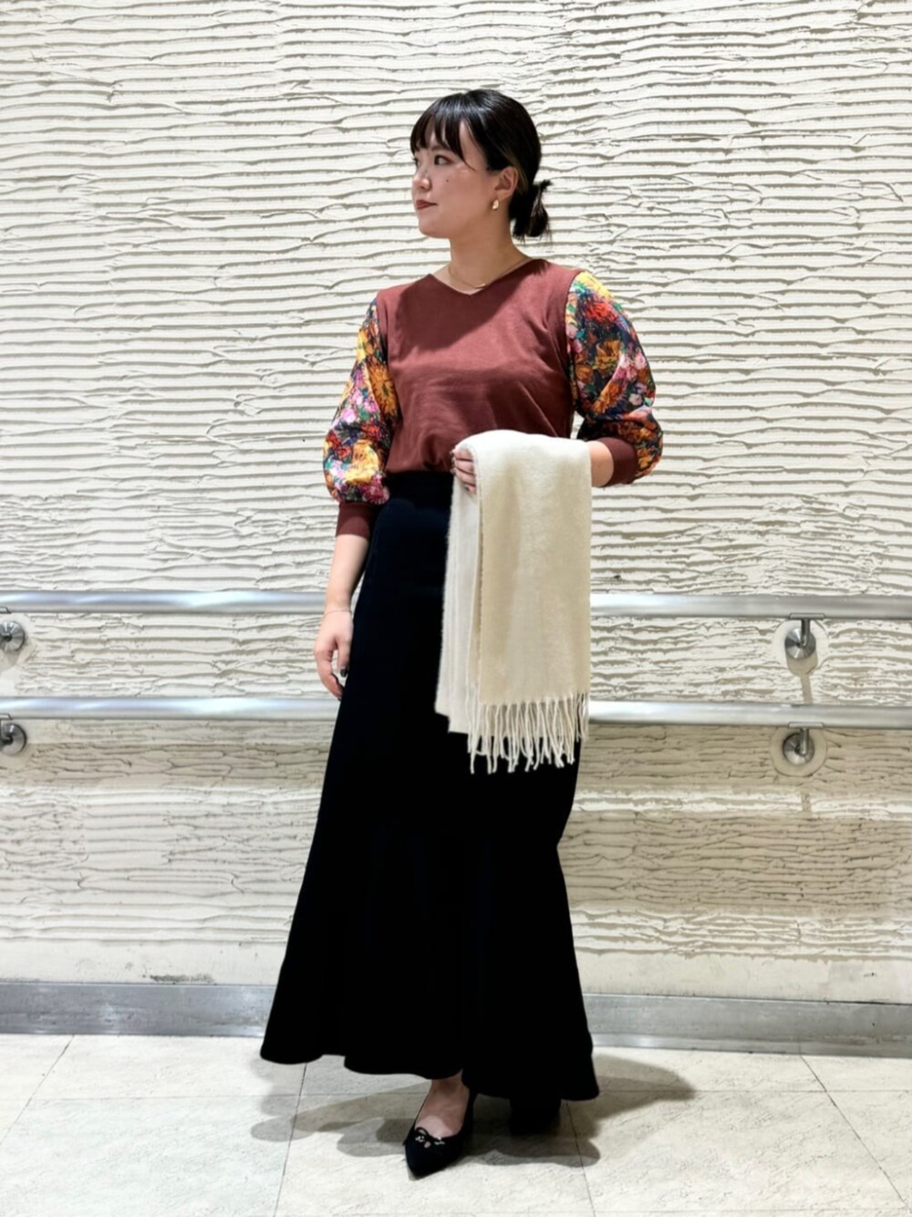 ブラウン系のニット/セーター、ブラック系のパンプス、ベージュ系のストール/ショールを着用したレディースの冬コーディネートの1枚目の写真