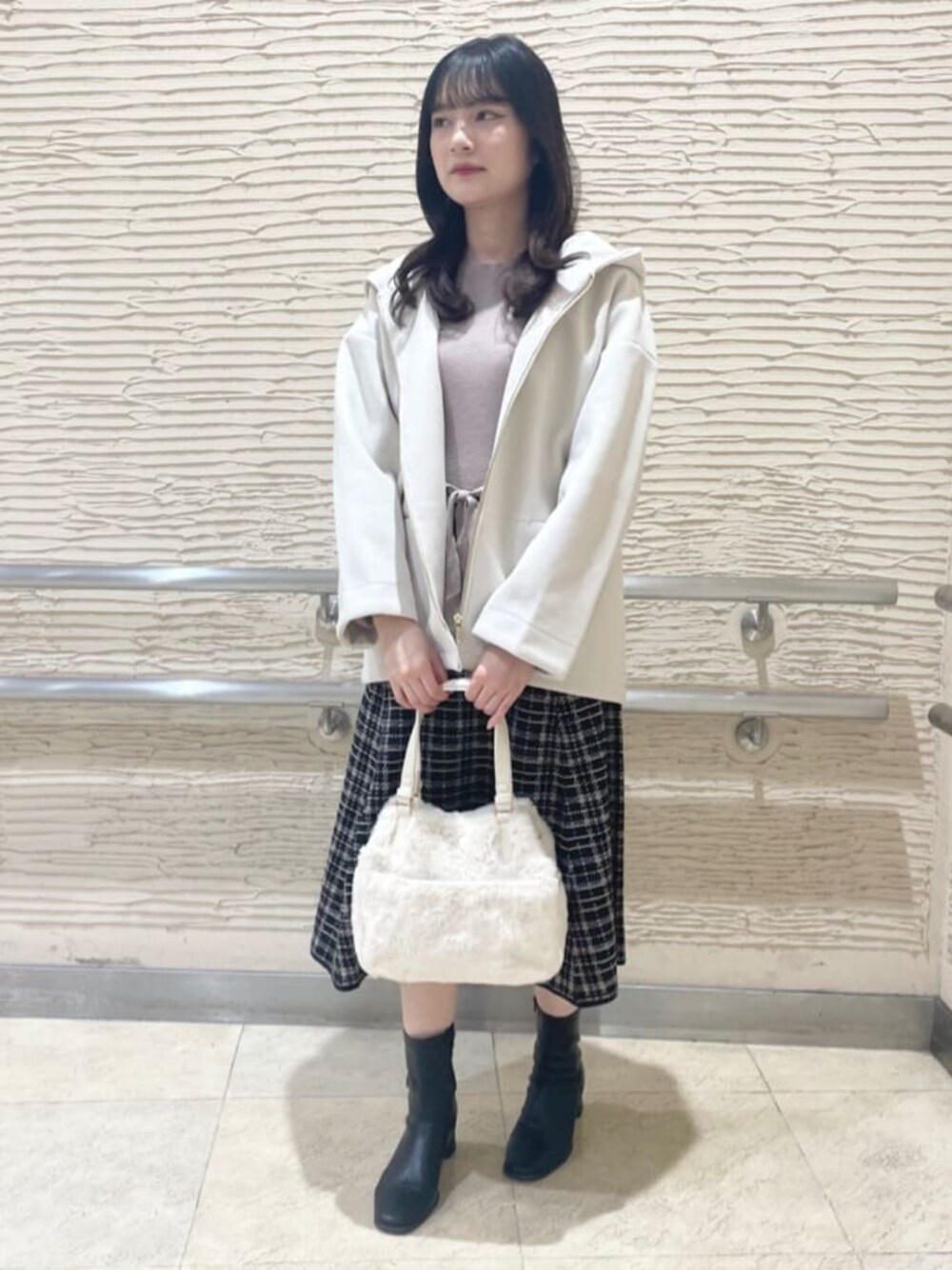 ブラック系のブーツ、ホワイト系のその他アウター、ベージュ系のワンピースを着用したレディースの冬コーディネートの1枚目の写真