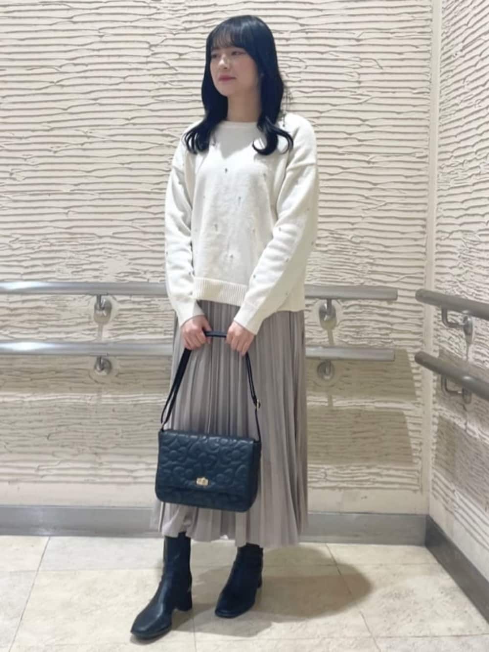 ブラック系のブーツ、ホワイト系のニット/セーター、ベージュ系のスカートを着用したレディースの冬コーディネートの1枚目の写真