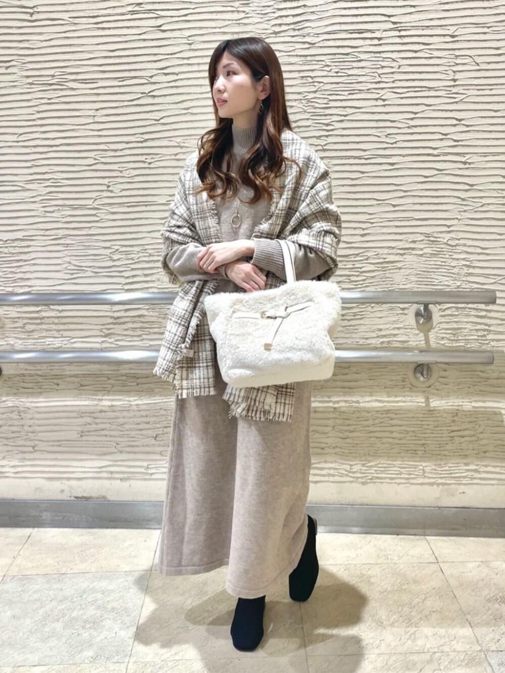 ブラック系のブーツ、ベージュ系のセットアップ、ベージュ系のストール/ショールを着用したレディースの冬コーディネートの1枚目の写真