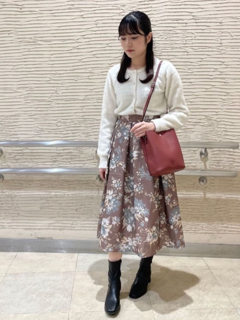 ブラック系のブーツ、ホワイト系のカーディガン/ボレロ、ブラウン系のスカートを着用したレディースの秋コーディネートの1枚目の写真
