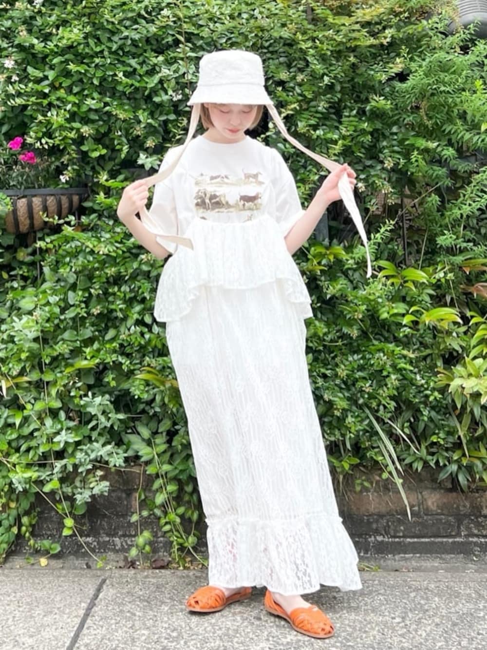 オレンジ系のパンプス、ホワイト系のスカート、ベージュ系のTシャツ/カットソーを着用したレディースの夏コーディネートの1枚目の写真