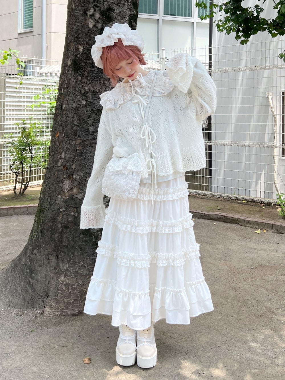 ホワイト系のハンドバッグ、ホワイト系のスカート、ホワイト系のブーツを着用したレディースの夏コーディネートの1枚目の写真
