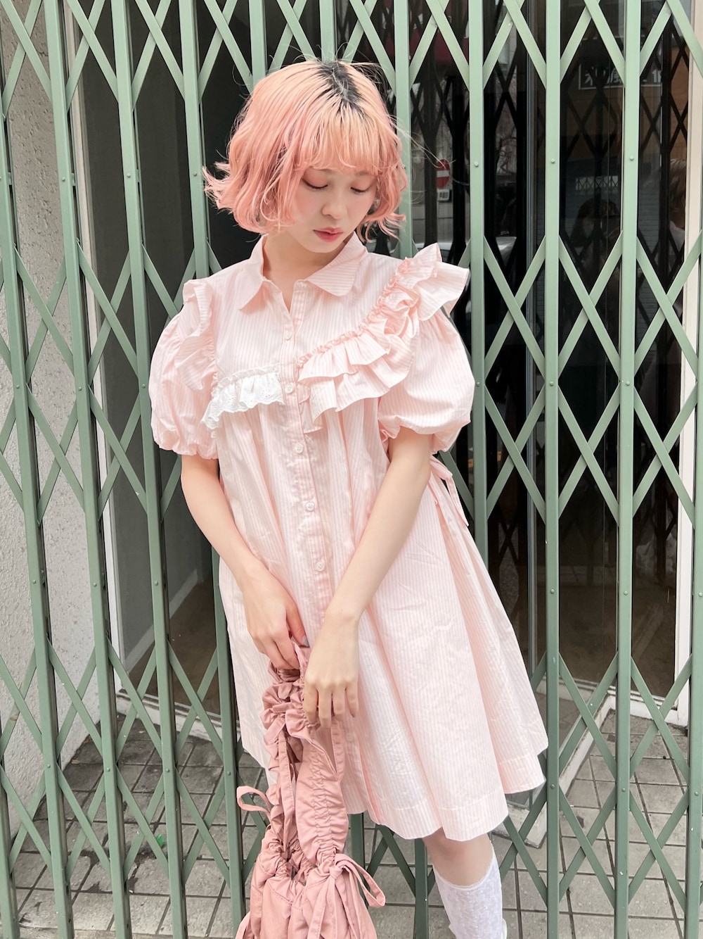 ピンク系のワンピース、ピンク系のトートバッグ、ホワイト系のスニーカーを着用したレディースの春コーディネートの1枚目の写真