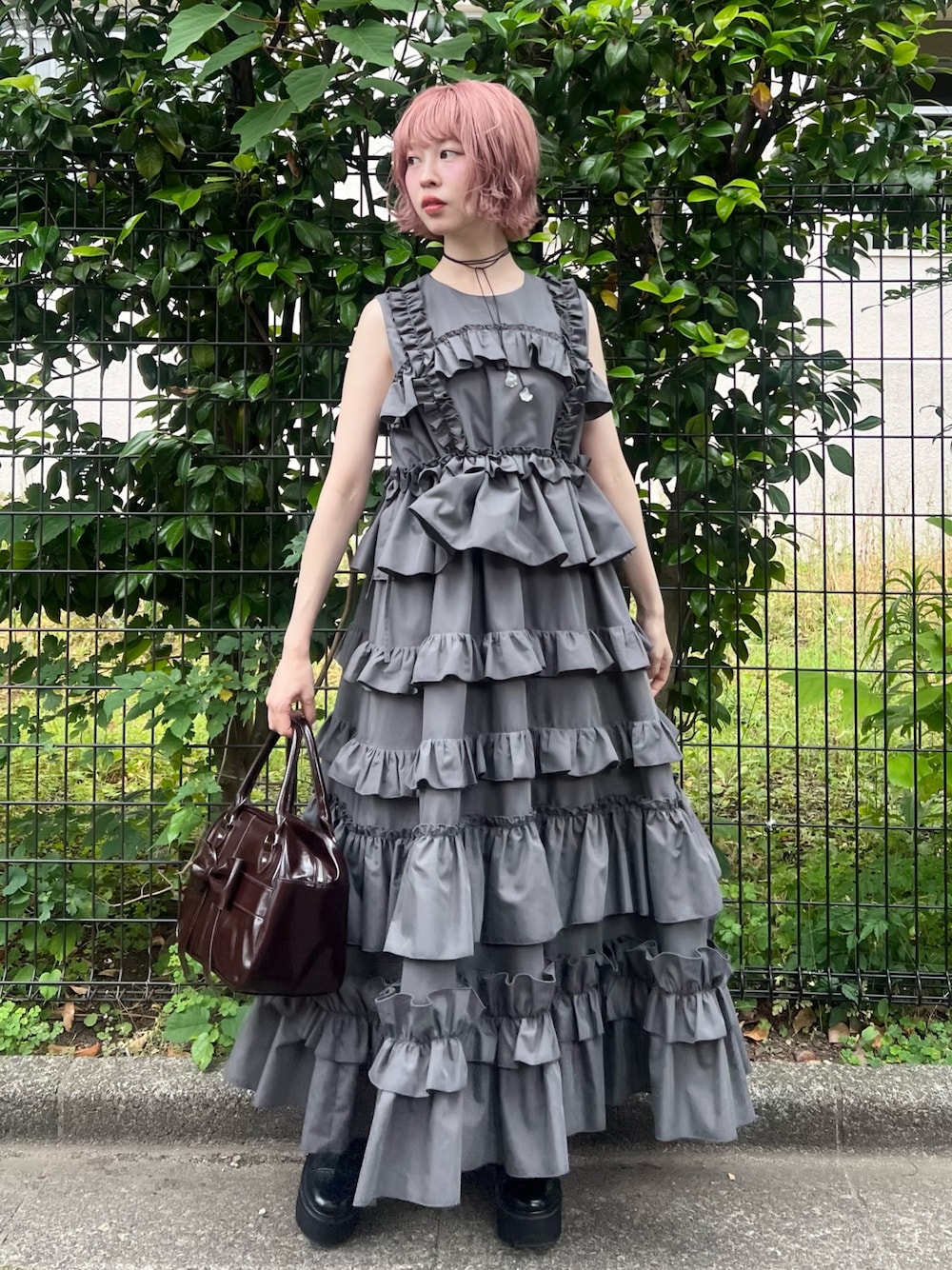 グレー系のワンピース、ブラウン系のハンドバッグ、ブラック系のブーツを着用したレディースの夏コーディネートの1枚目の写真