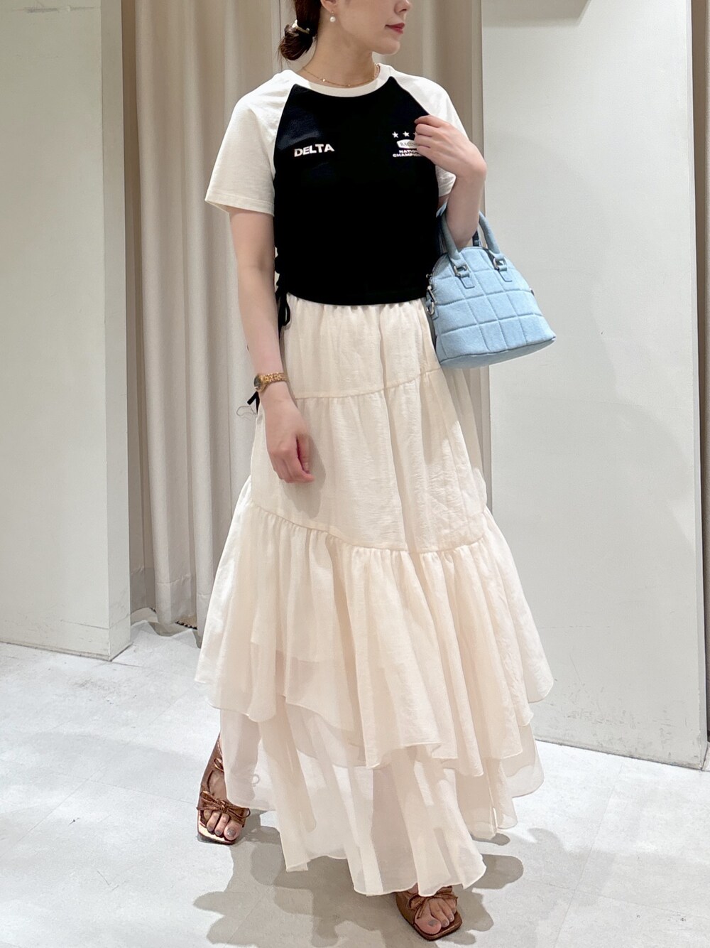 ブラック系のTシャツ/カットソー、ブルー系のトートバッグ、ホワイト系のスカートを着用したレディースの夏コーディネートの1枚目の写真