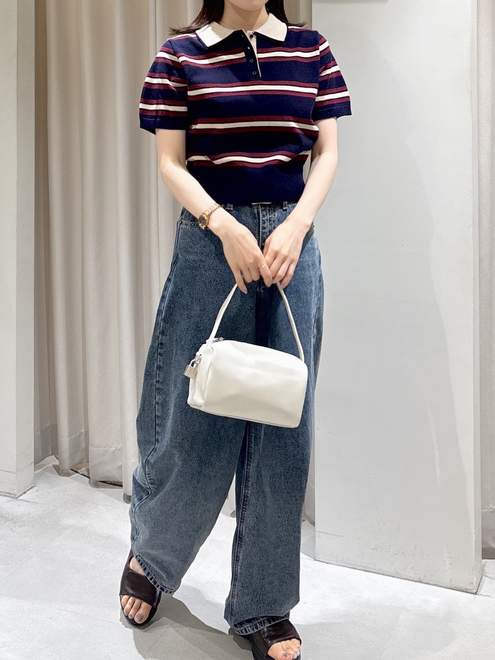 ブルー系のニット/セーター、ホワイト系のハンドバッグ、ブルー系のデニムパンツを着用したレディースの夏コーディネートの1枚目の写真