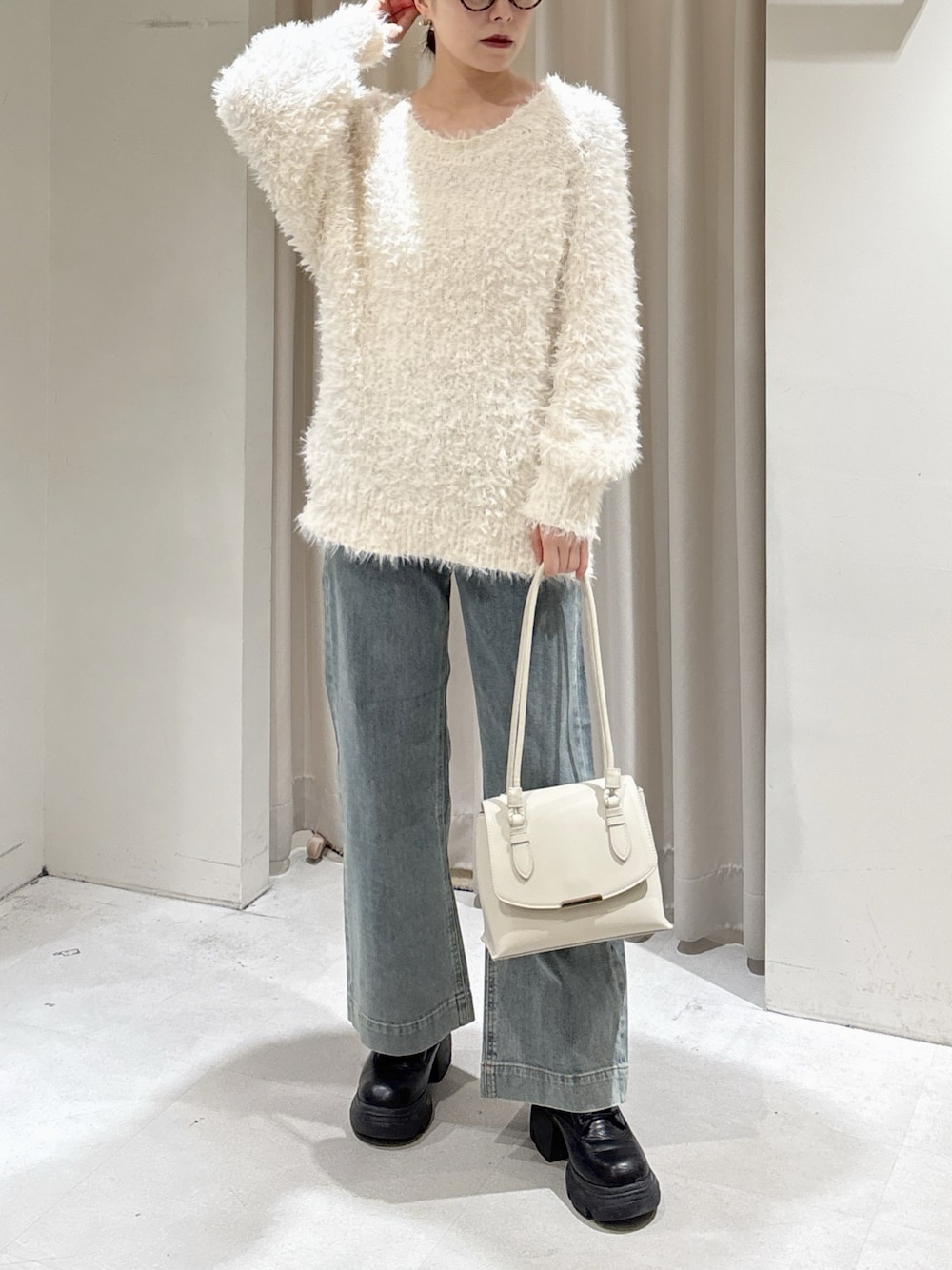 ホワイト系のニット/セーター、ブルー系のデニムパンツ、ホワイト系のショルダーバッグを着用したレディースの冬コーディネートの1枚目の写真