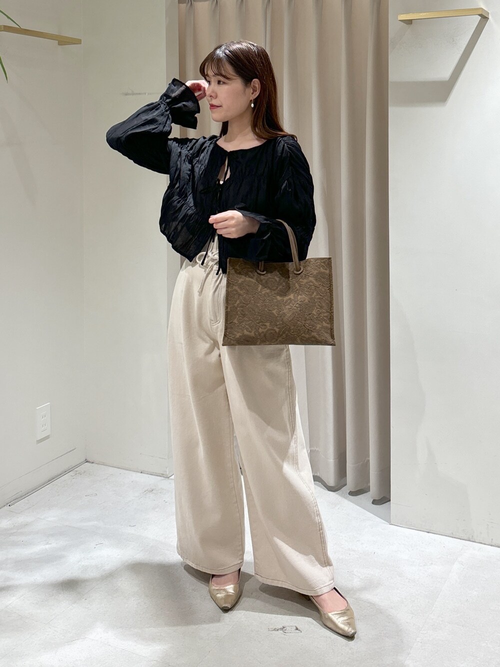 ブラウン系のトートバッグ、ホワイト系のデニムパンツ、ゴールド系のパンプスを着用したレディースの春コーディネートの1枚目の写真