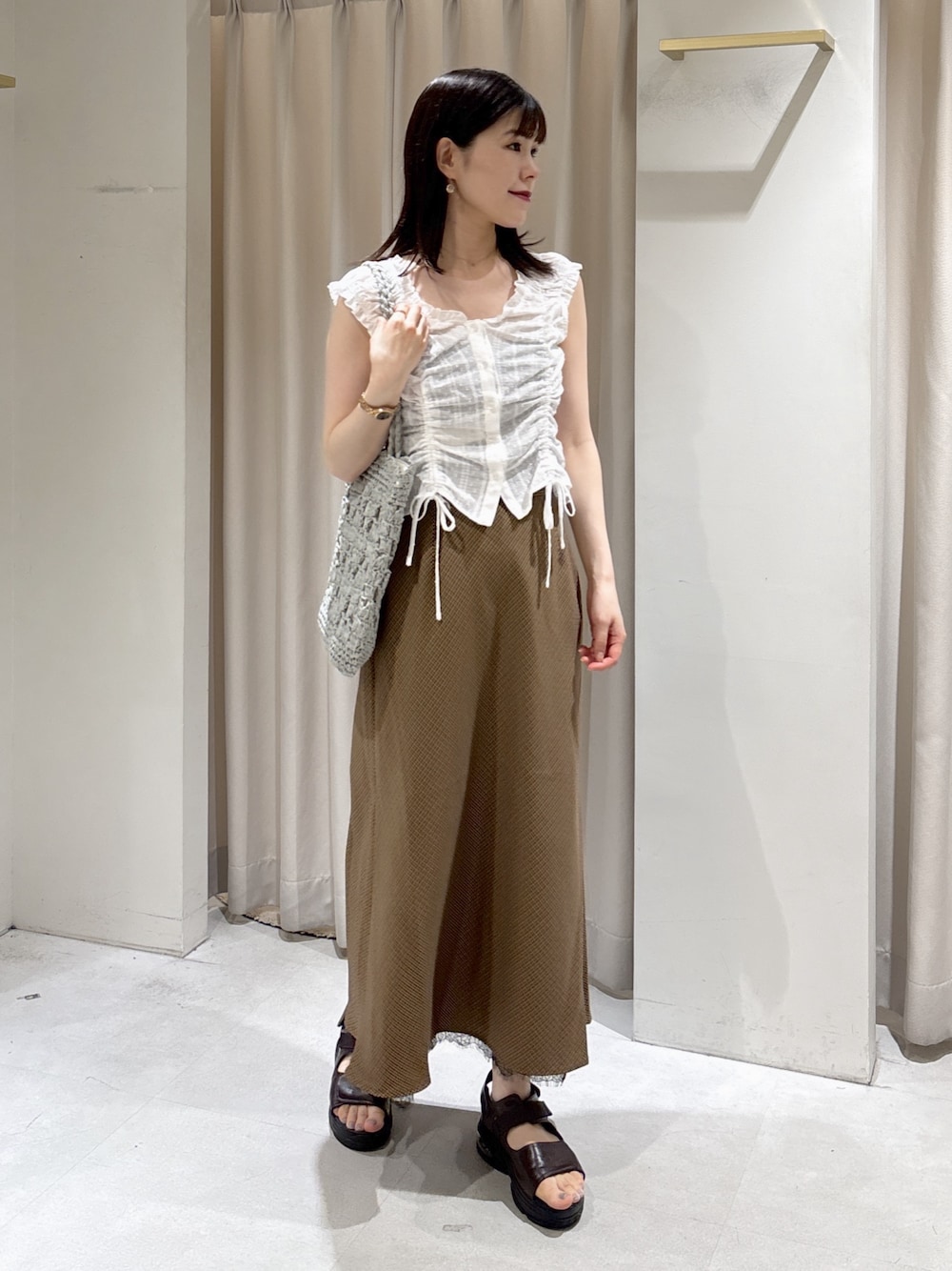 ホワイト系のシャツ/ブラウス、ベージュ系のスカート、ブラウン系のサンダルを着用したレディースの夏コーディネートの1枚目の写真