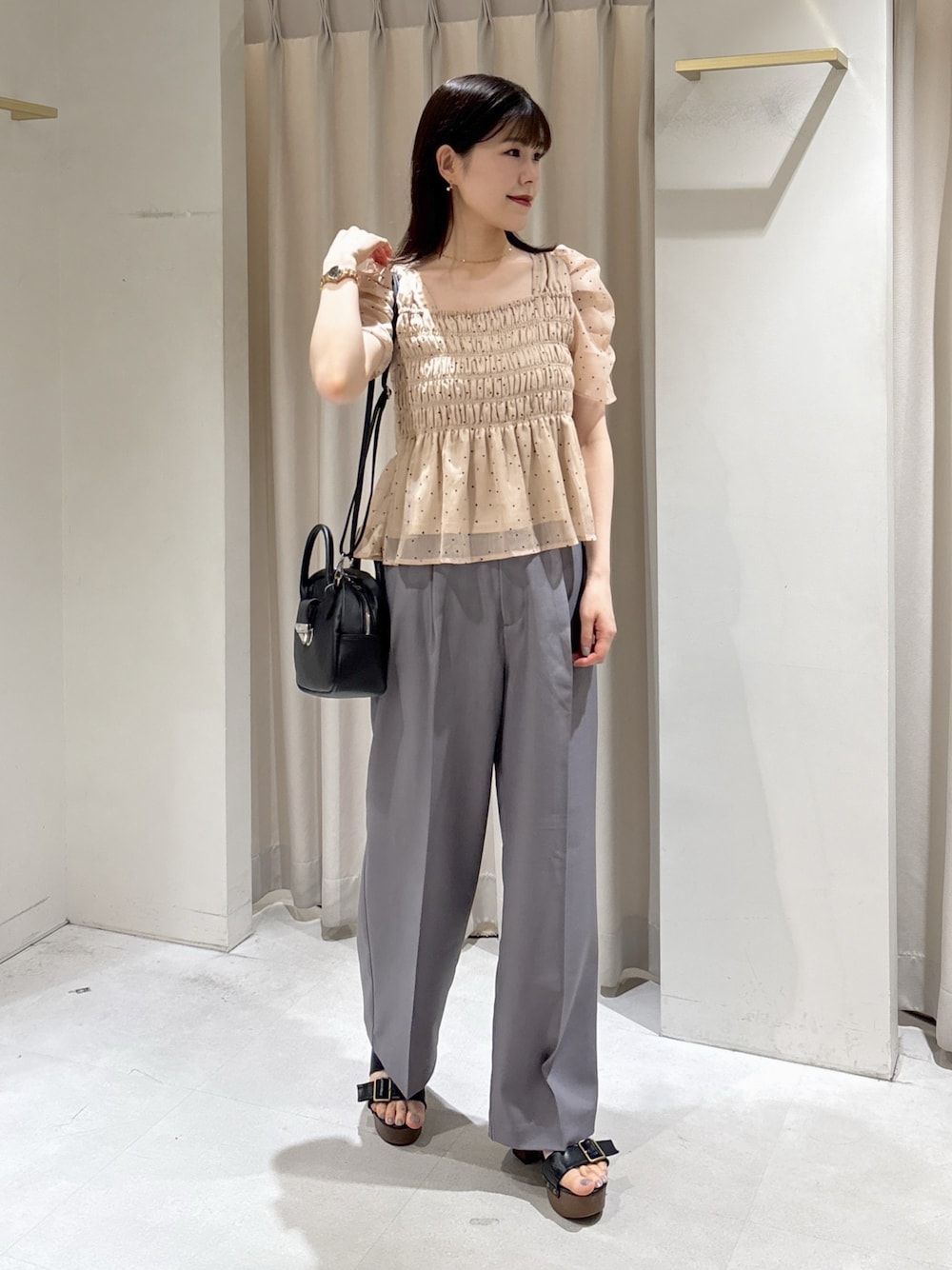 ピンク系のシャツ/ブラウス、ブラック系のハンドバッグ、グレー系のスラックスを着用したレディースの夏コーディネートの1枚目の写真