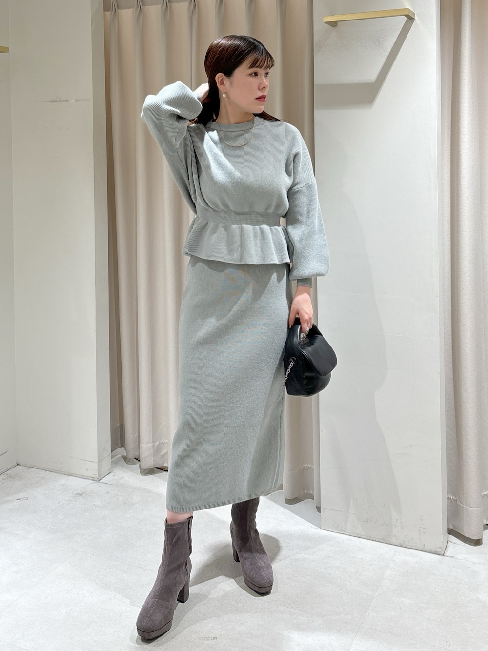 グリーン系のワンピース、ブラック系のショルダーバッグ、グレー系のブーツを着用したレディースの冬コーディネートの1枚目の写真