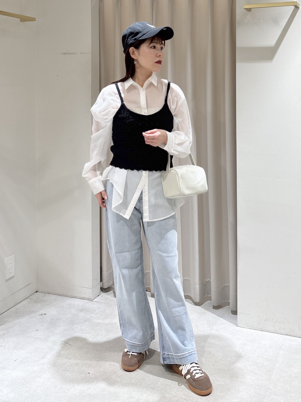 ホワイト系のシャツ/ブラウス、ブラック系のニット/セーター、ブルー系のデニムパンツを着用したレディースの春コーディネートの1枚目の写真