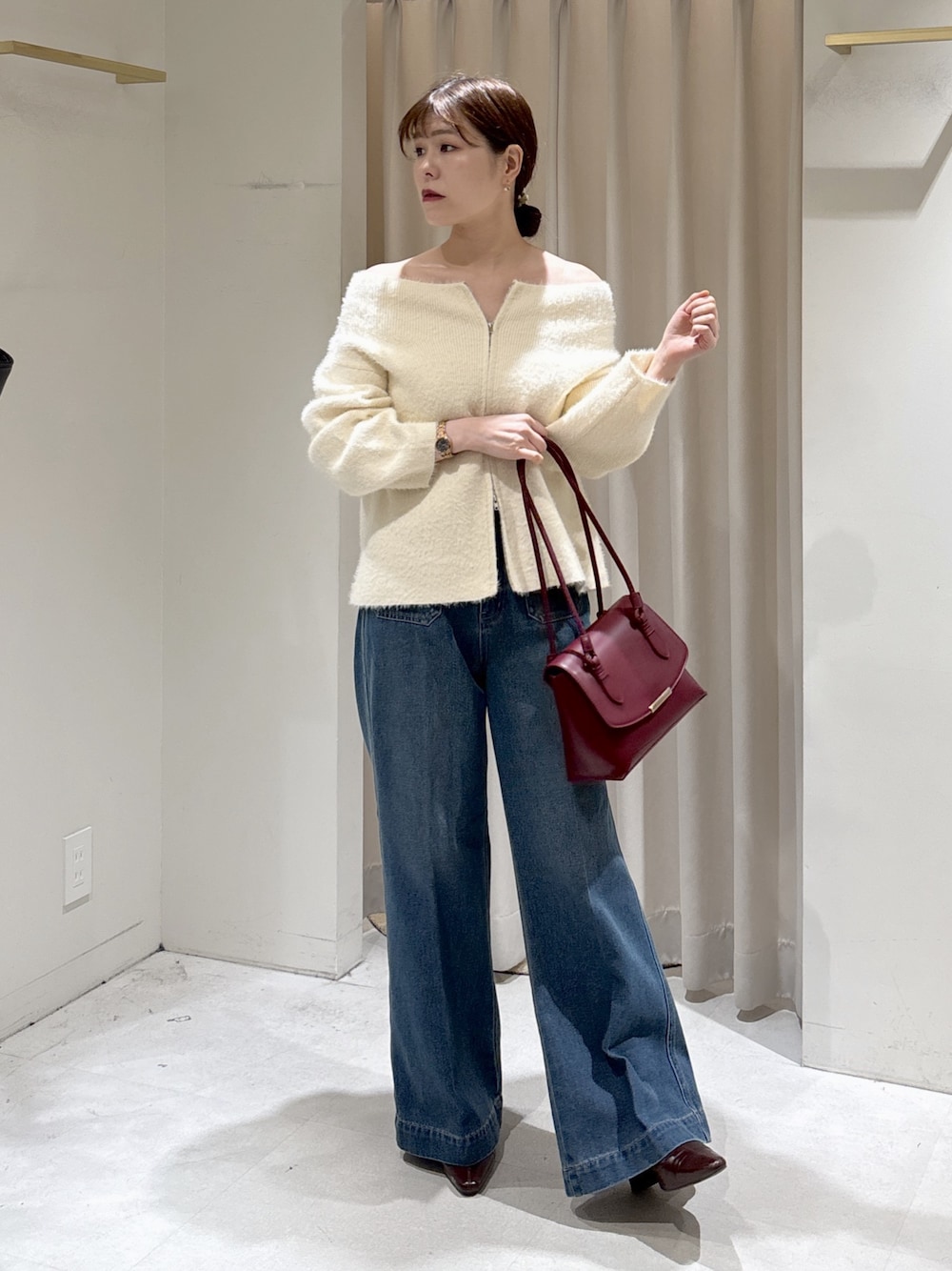 ホワイト系のニット/セーター、レッド系のトートバッグ、ブルー系のデニムパンツを着用したレディースの秋コーディネートの1枚目の写真