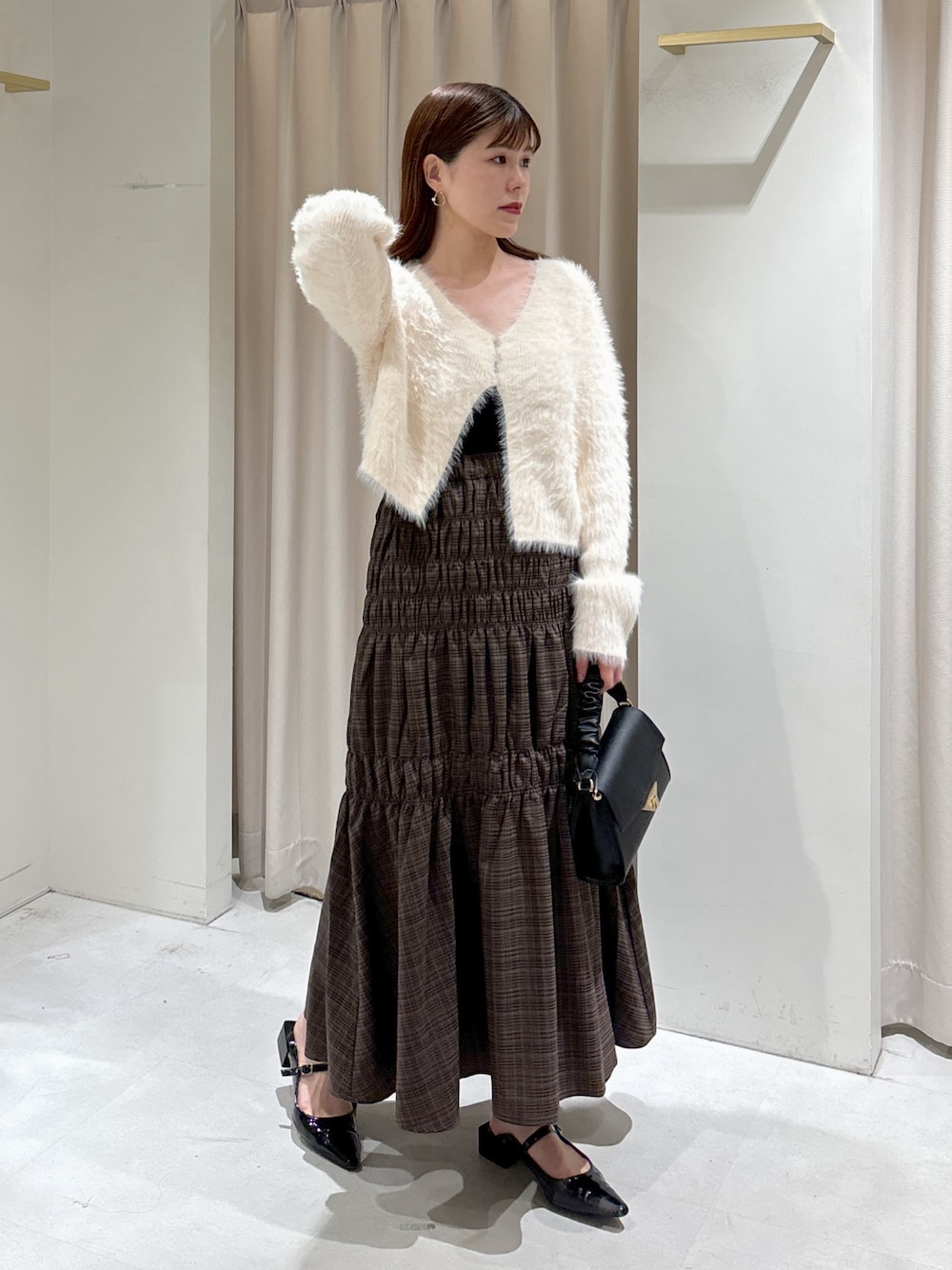 ホワイト系のカーディガン/ボレロ、ブラック系のキャミソール、ブラック系のショルダーバッグを着用したレディースの秋コーディネートの1枚目の写真