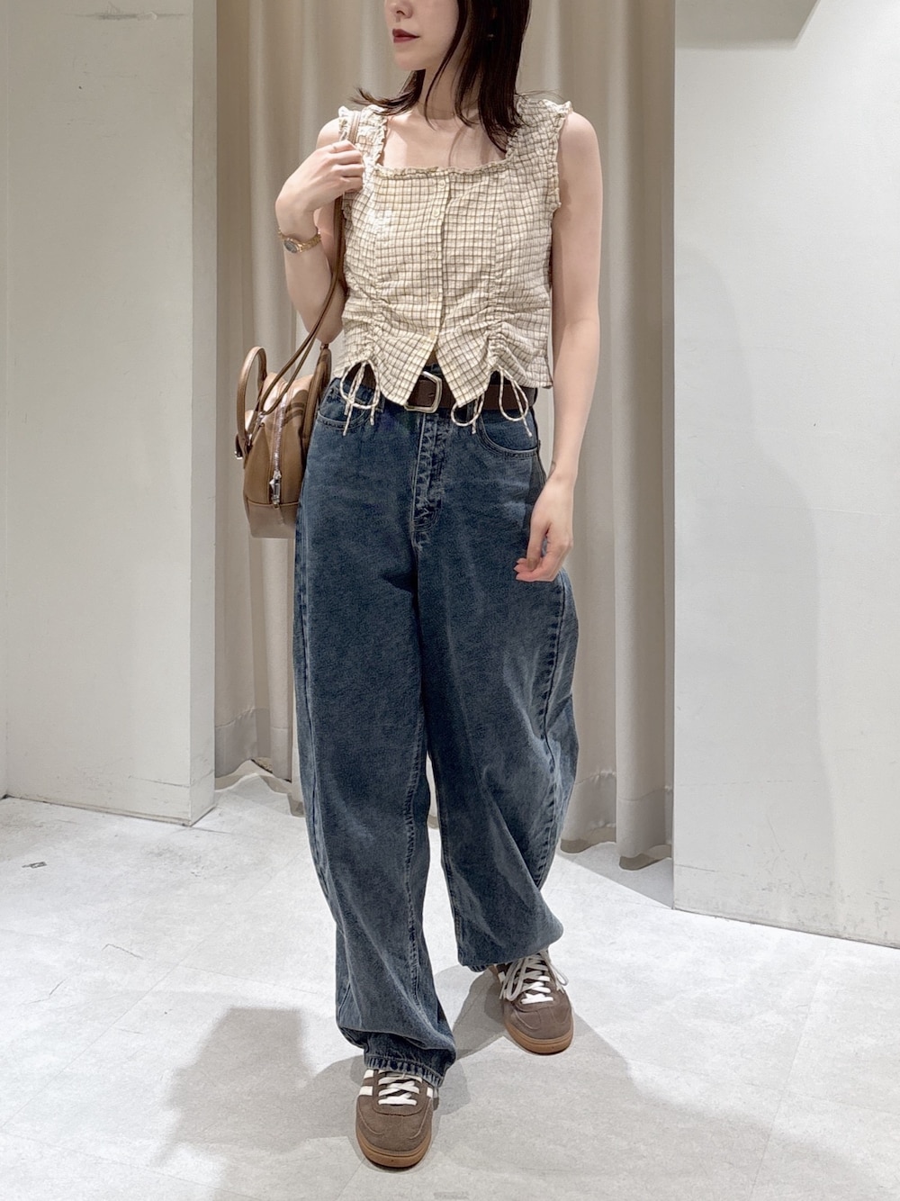 ベージュ系のシャツ/ブラウス、ブルー系のデニムパンツ、ブラウン系のハンドバッグを着用したレディースの春コーディネートの1枚目の写真